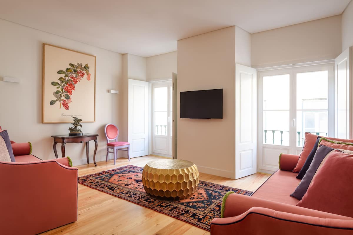 Un salon avec une table basse ronde, un canapé, un fauteuil et une estampe botanique encadrée au mur.