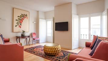 A living room with a round coffee table, a sofa, a chair, and a framed botanical print on the wall.