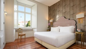 Une chambre avec un grand lit, une chaise en bois, une fenêtre donnant sur un beau paysage et un mur à motifs.