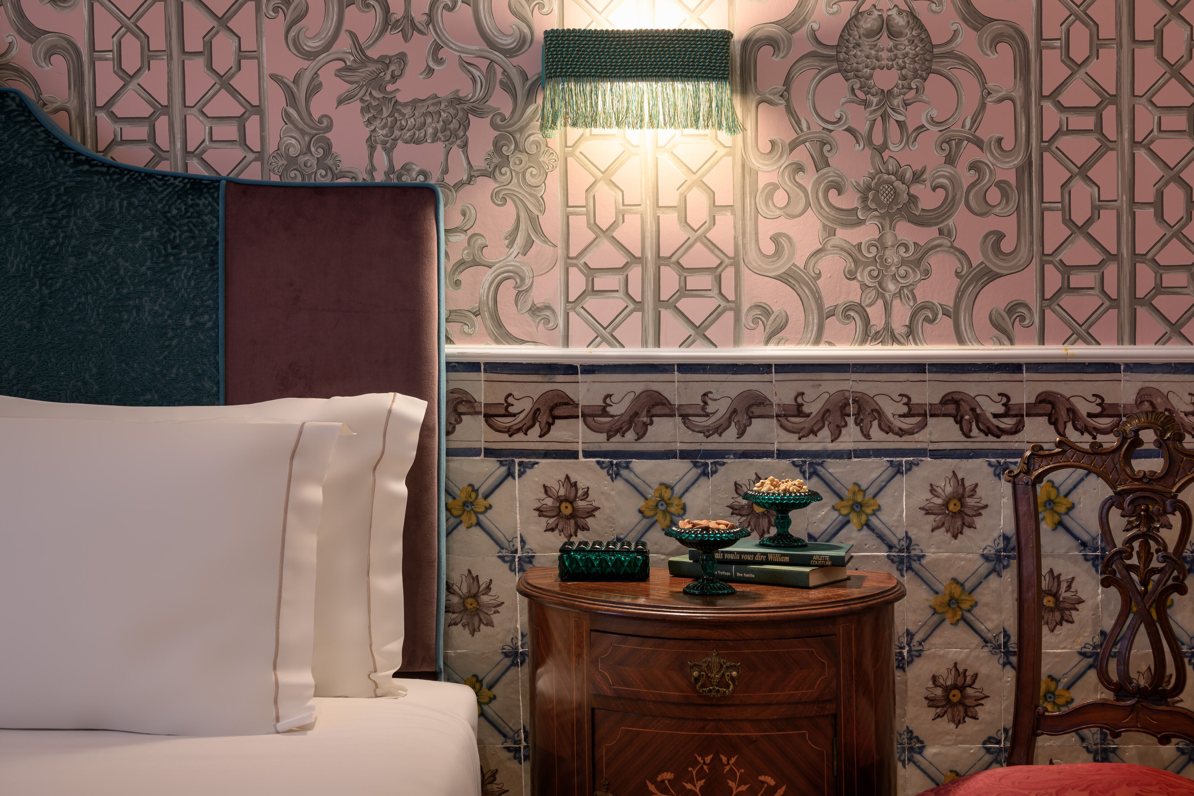 Un dormitorio con una cama, una mesita de noche y una pared con azulejos decorativos.