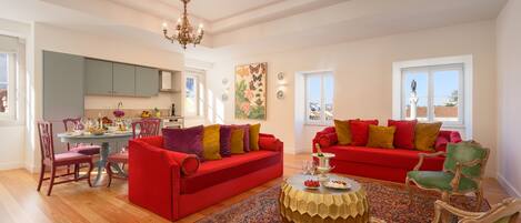 Amplia sala de estar con sofás rojos, una mesa de centro redonda y un comedor con mesa y sillas.