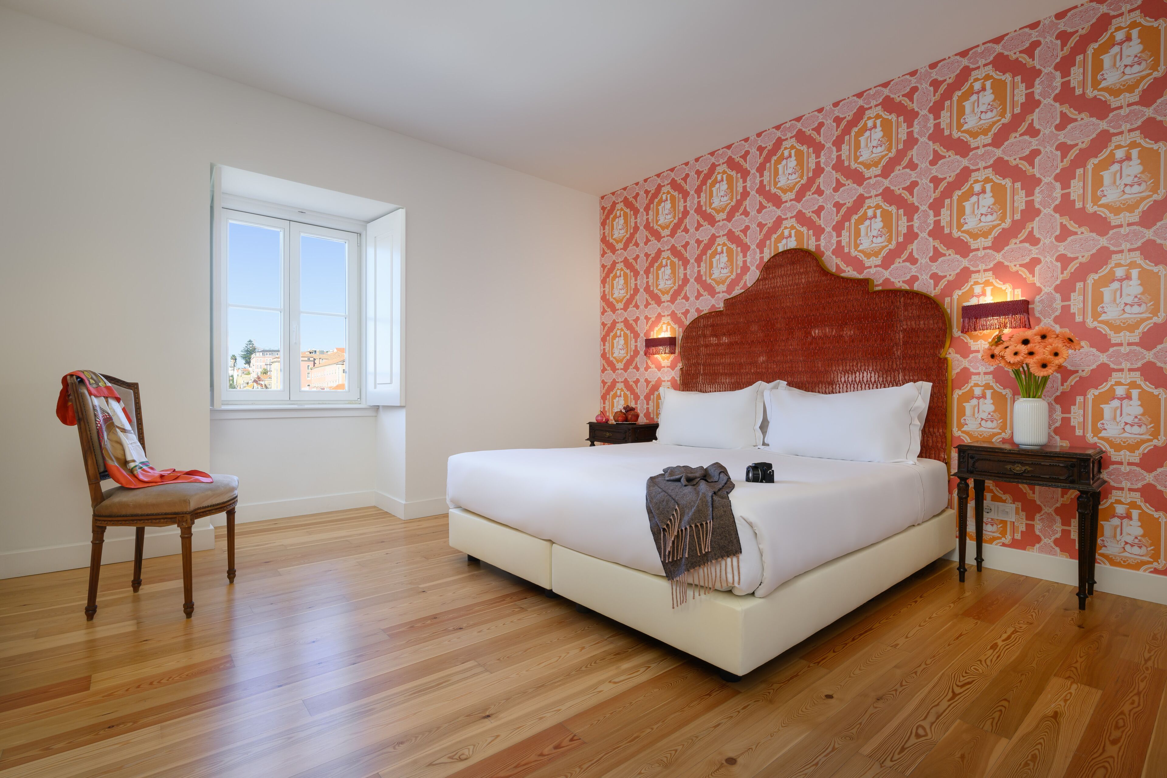 Un dormitorio con una cama grande, una silla, una mesita de noche y una ventana.