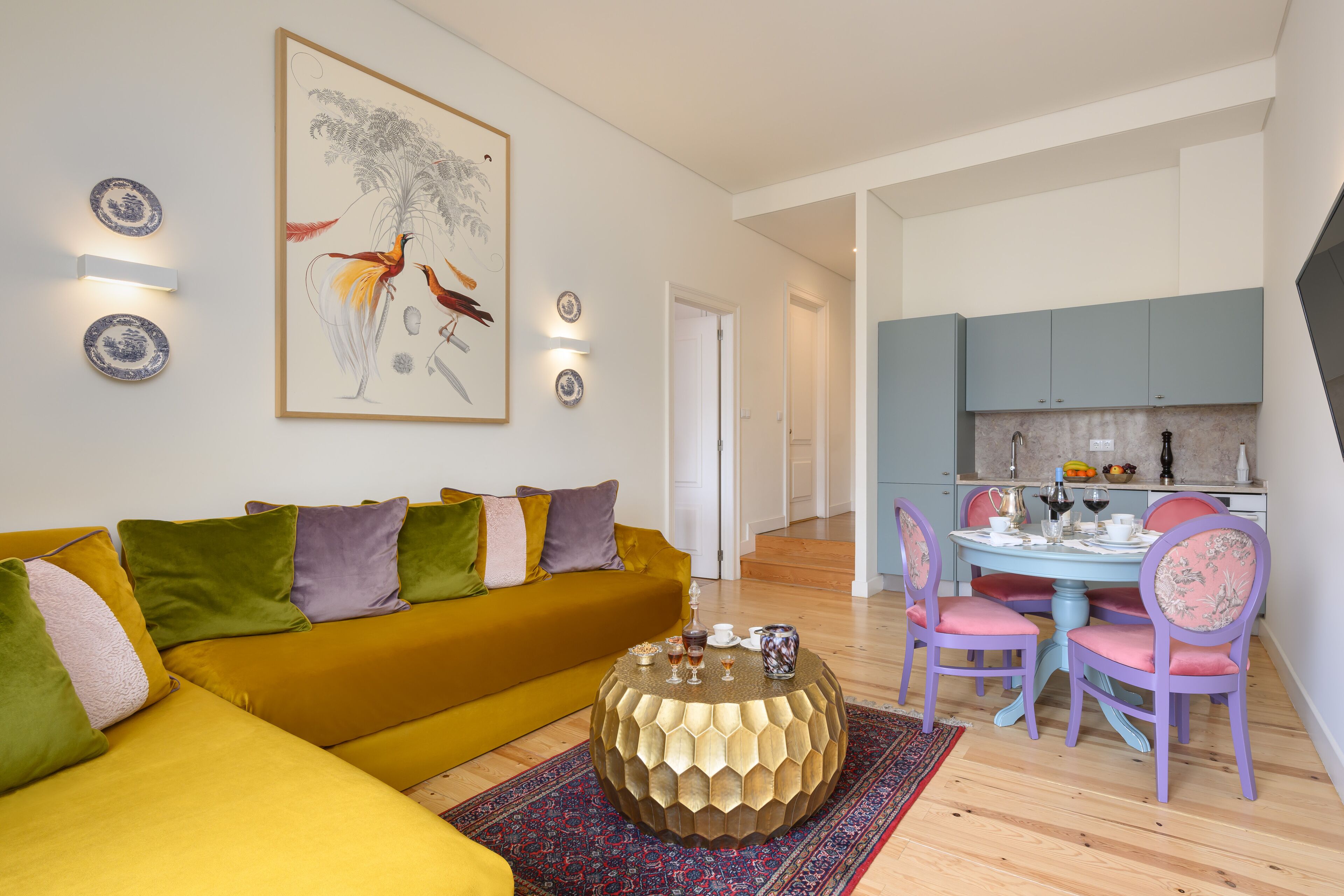 A living room with a yellow sofa, a round coffee table, and a dining area with a table and chairs.