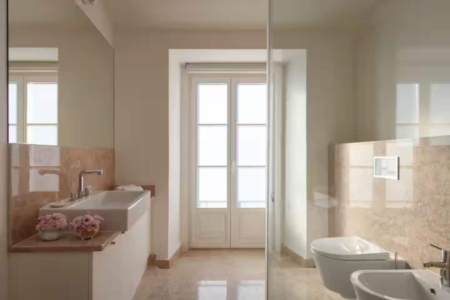 A modern bathroom with a large mirror, a sink, and a toilet.