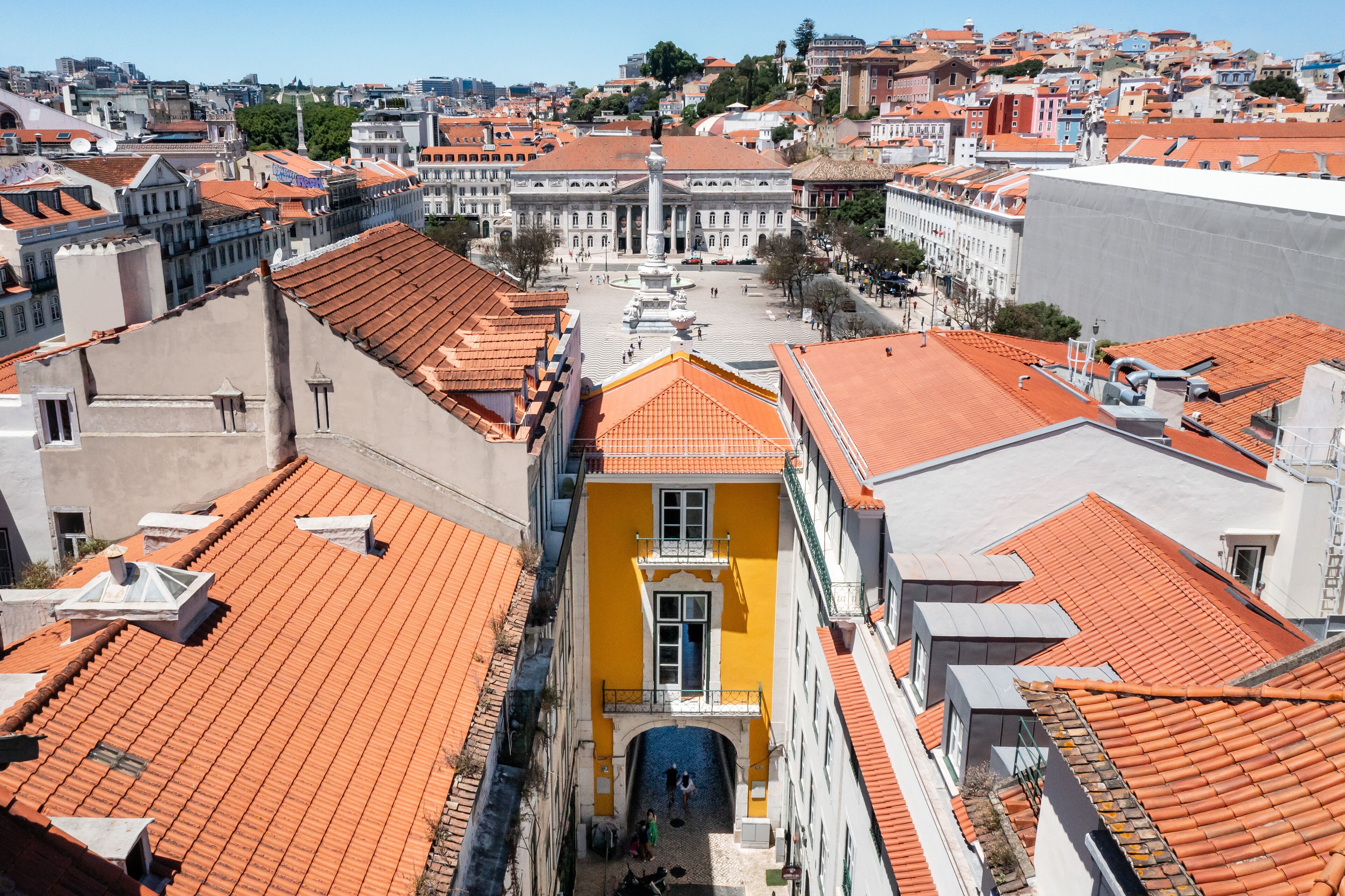 A historic building with a central courtyard, red-tiled roofs, and a prominent statue.