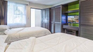 Una camera d'albergo con due letti, un armadio e un televisore.