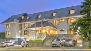 Un hotel moderno con un ingresso ben visibile, diverse bandiere e una scalinata che conduce all'ingresso.