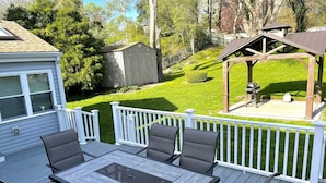 Eine Terrasse mit Tisch und Stühlen, ein überdachter Grillplatz und ein Geräteschuppen im Garten.