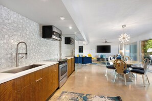 A modern kitchen with a white tiled backsplash, wooden cabinets, and stainless steel appliances. - Joplin House - Poolside Paradise w/ Amazing Views! (Palm Springs)