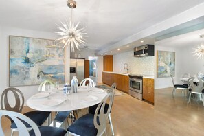 Una cocina moderna con una isla central, electrodomésticos de acero inoxidable y un comedor con una mesa redonda y sillas.