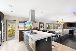 Cocina moderna con una isla central, electrodomésticos integrados y un comedor con vistas.