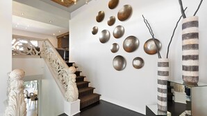 Un intérieur moderne agrémenté d’un escalier, d’œuvres d’art décoratives murales et d’un vase original.