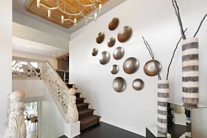 Un interior moderno con una escalera, arte decorativo en la pared y un jarrón original.