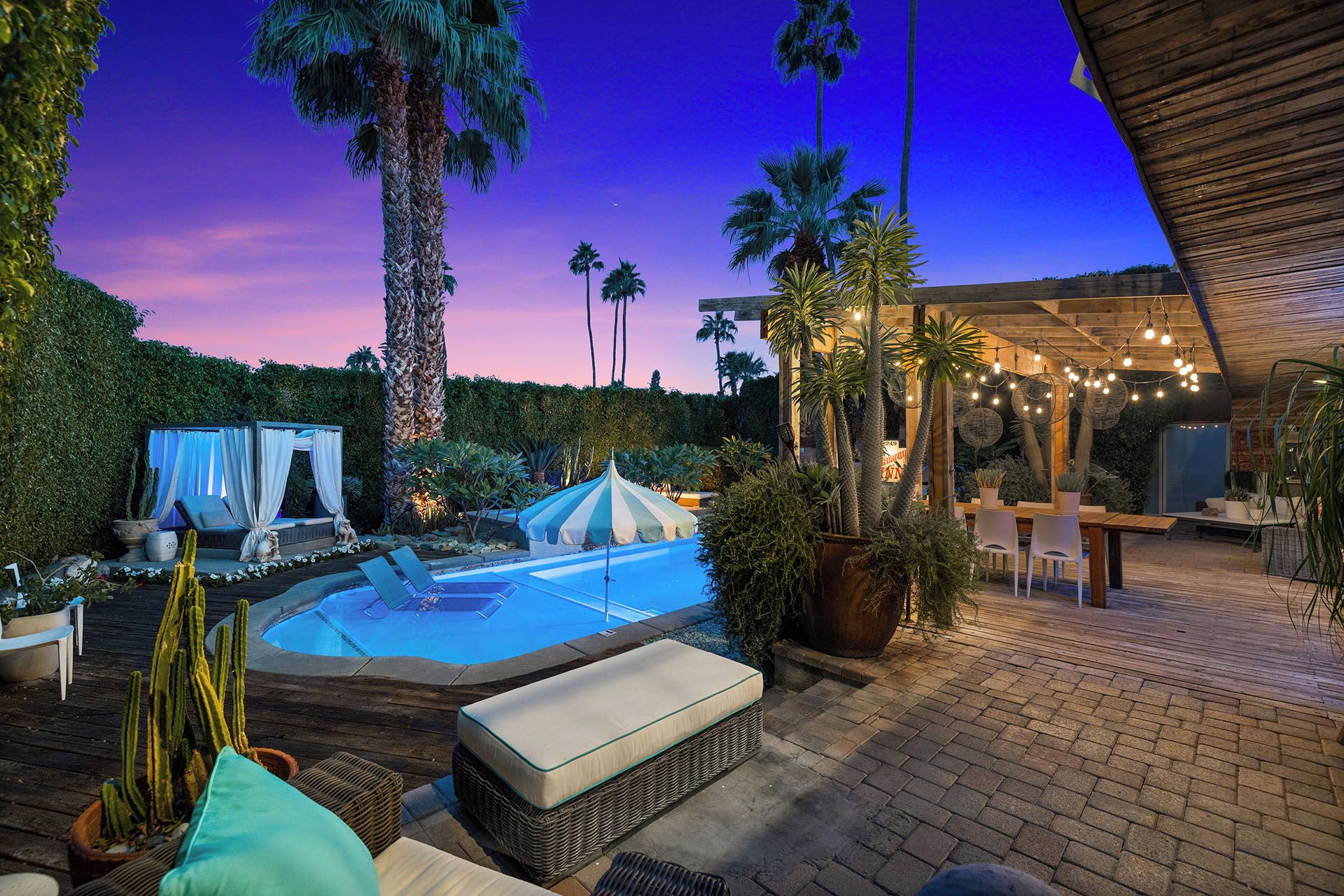 A pool area with lounge chairs, a small tent, and a wooden deck.