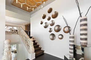 A modern interior with a staircase, decorative wall art, and a unique vase. - Joplin House - Poolside Paradise w/ Amazing Views! (Palm Springs)