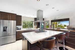 Een moderne keuken met een centraal eiland, roestvrijstalen apparatuur en donker houten kastjes.