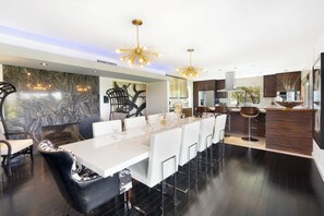 A modern kitchen with a marble backsplash, a dining area with white chairs, and a bar area with stools. - Joplin House - Poolside Paradise w/ Amazing Views! (Palm Springs)