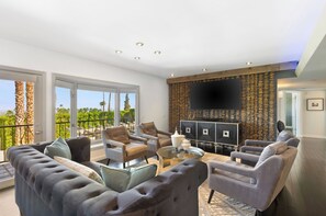Una sala de estar moderna con un televisor de pantalla plana grande, asientos cómodos y vistas al exterior.