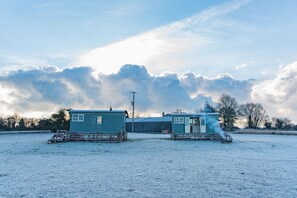 A snow-covered field with two small blue buildings and a large barn. - Romney Marsh Huts by Bloom Stays  -  beautiful shepherds hut that sleeps 4 guests  in 2 bedrooms (Ashford)