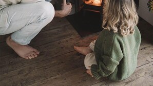 Un hombre y un niño sentados en el suelo frente a una chimenea.