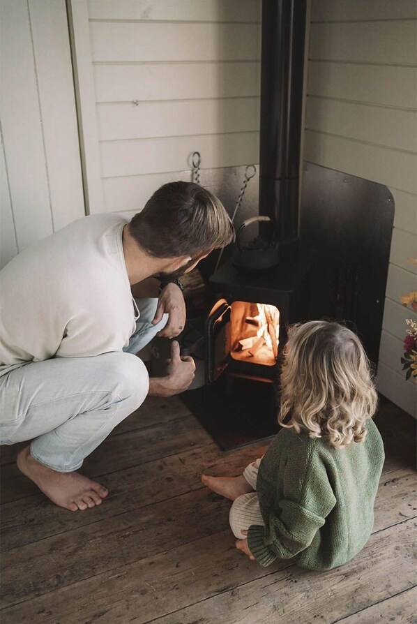 A man and a child sitting on the floor in front of a fireplace. - Romney Marsh Huts by Bloom Stays - beautiful shepherds hut that sleeps 4 guests in 2 bedrooms (Ashford)