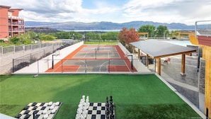Een tennisbaan met uitzicht op bergen, een groen gazon en een schaakbord.
