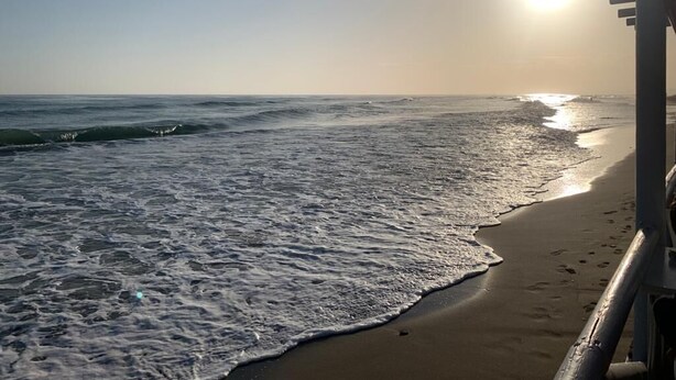 Ein Strand mit Wellen, einem klaren Himmel und Sonnenuntergang oder -aufgang.