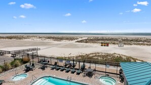 Un resort sulla spiaggia con area piscina, poltrone prendisole e vista sulla spiaggia e sull'oceano.