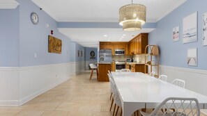 A modern kitchen with wooden cabinets, stainless steel appliances, and a white dining table. - 4br Beachfront Condo with Ocean Views and Pool (Wildwood Crest)