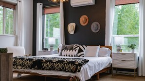 A bedroom with a bed, a nightstand, a dresser, and a window with curtains.