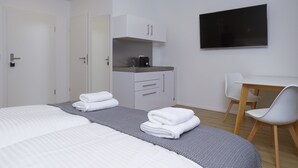 Ein modernes Hotelzimmer mit einem großen Bett, einem Schreibtisch, einem Flachbildfernseher und einer Küchenzeile.