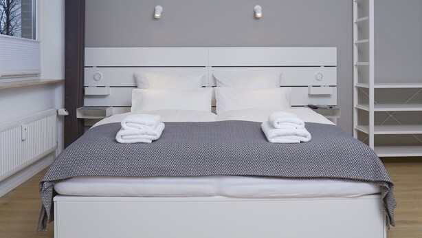 Ein modernes Hotelzimmer mit einem großen Bett, einem weißen Kopfteil und Nachttischen.