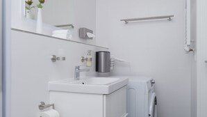 Ein kleines, modernes Badezimmer mit Toilette, Waschbecken und Waschmaschine.