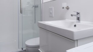 Ein modernes Badezimmer mit einer Glasdusche, einem weißen Waschbecken und einer Toilette.