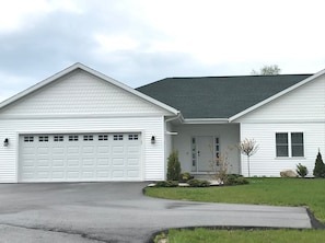 Stunning two-story home with a central entrance, garage, and beautifully manicured lawn.