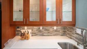 Una cocina con armarios de madera, salpicadero de azulejos y un lavabo de acero inoxidable.