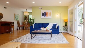 Una sala de estar con un sofá azul, una mesa de centro y un comedor con sillas y una mesa.