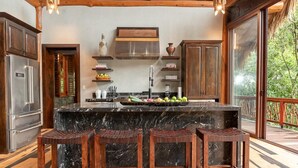 A spacious kitchen with a large island, wooden cabinets, and a thatched ceiling. - Valley Stream Private Eden (St. Margaret's Village)