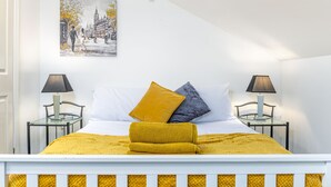 A neatly arranged bedroom with a bed, two bedside tables, a lamp on each, and a painting on the wall. - Liquorice Suite (Lincoln)