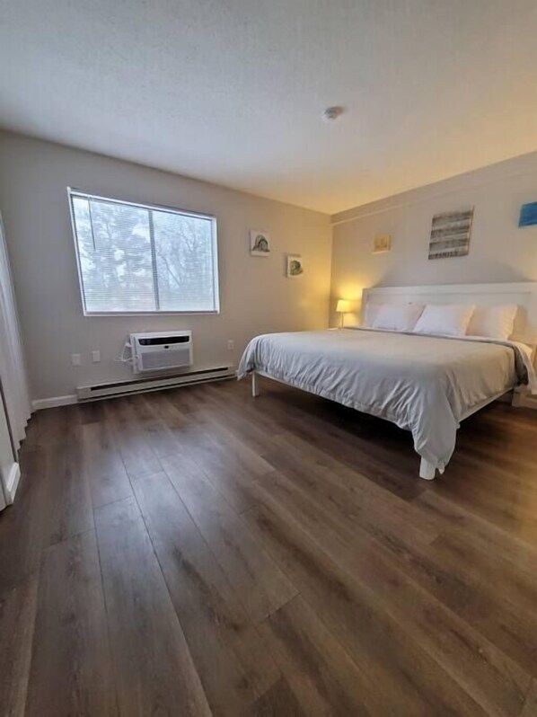 A bedroom with a large bed, a window, and a heater.