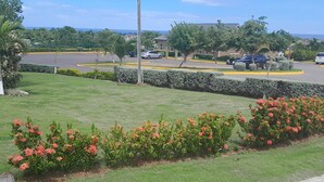 Un estacionamiento con coches, un edificio y una zona verde con flores.