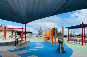A playground with a blue play area, red structures, and a dragon sculpture.
