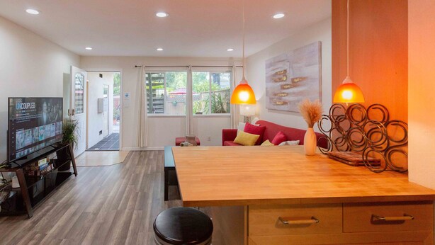 A modern kitchen with a wooden countertop, a dining table, and a TV on a stand. - 💎Cozy 1B/1B in a prime location • 🌲AC/ 1000mb wifi/ Washer, dryer/ more… (Sunnyvale)