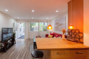 A modern kitchen with a wooden countertop, a dining table, and a TV on a stand.