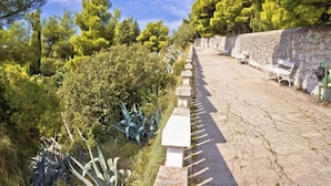 A pathway lined with stone benches and dense greenery, leading towards a stone wall. - Luxury Suite Jasmin-Two Bedroom Suite with Hot Tub (Split)