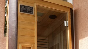 A sauna with a wooden interior, a small shelf with a statue, and a glass door. - Luxury Suite Jasmin-Two Bedroom Suite with Hot Tub (Split)