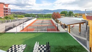Una cancha de tenis con vistas a montañas, un césped verde y un tablero de ajedrez.