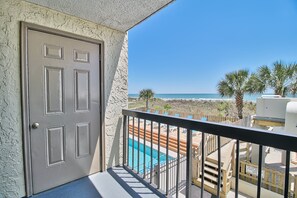 Een balkon met zwembad, een deur en uitzicht op strand en zee.