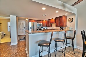 A modern kitchen with a central island, bar stools, and built-in appliances.