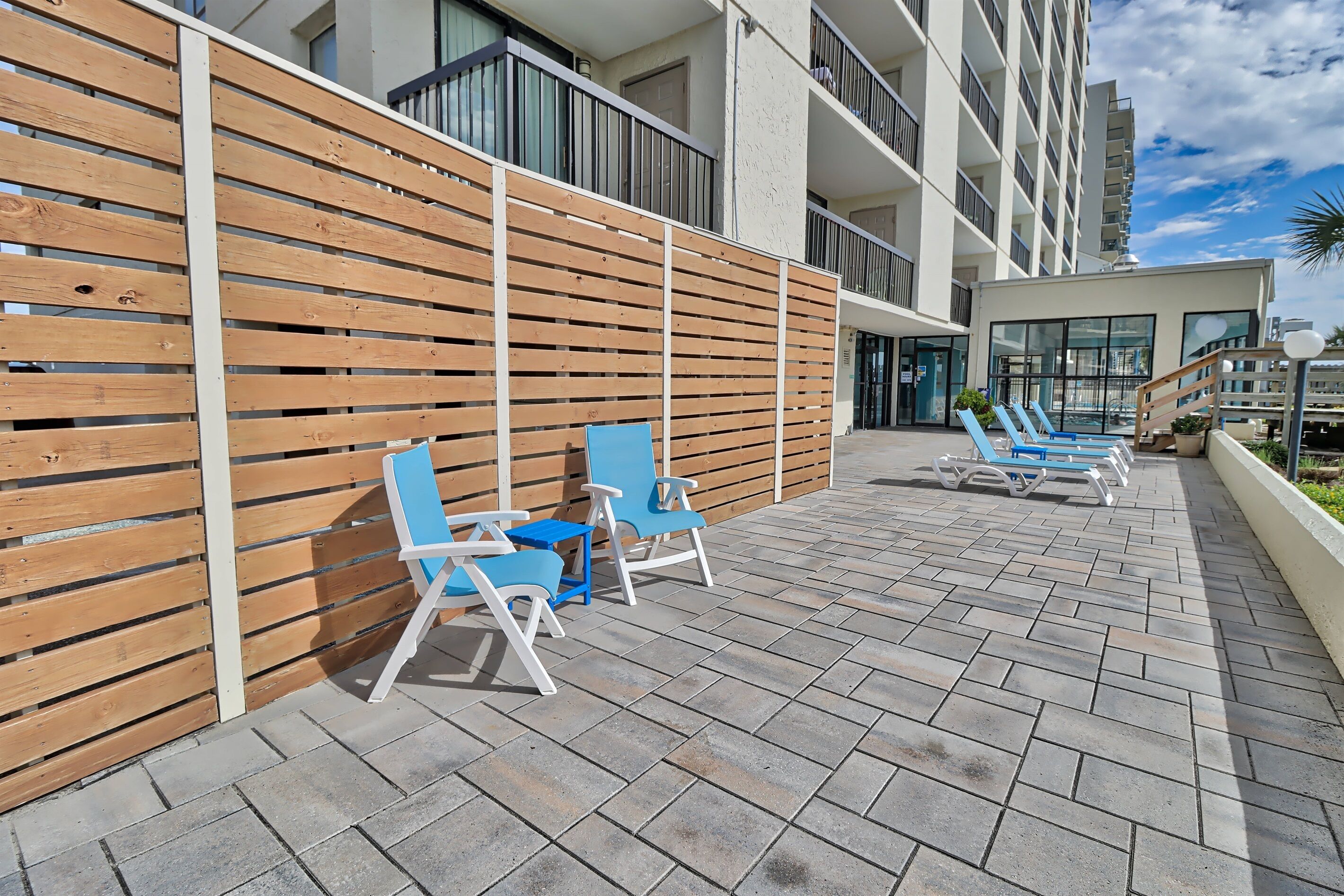 Una terrazza sul tetto con listelli di legno, poltrone da lounge blu e una zona piscina.